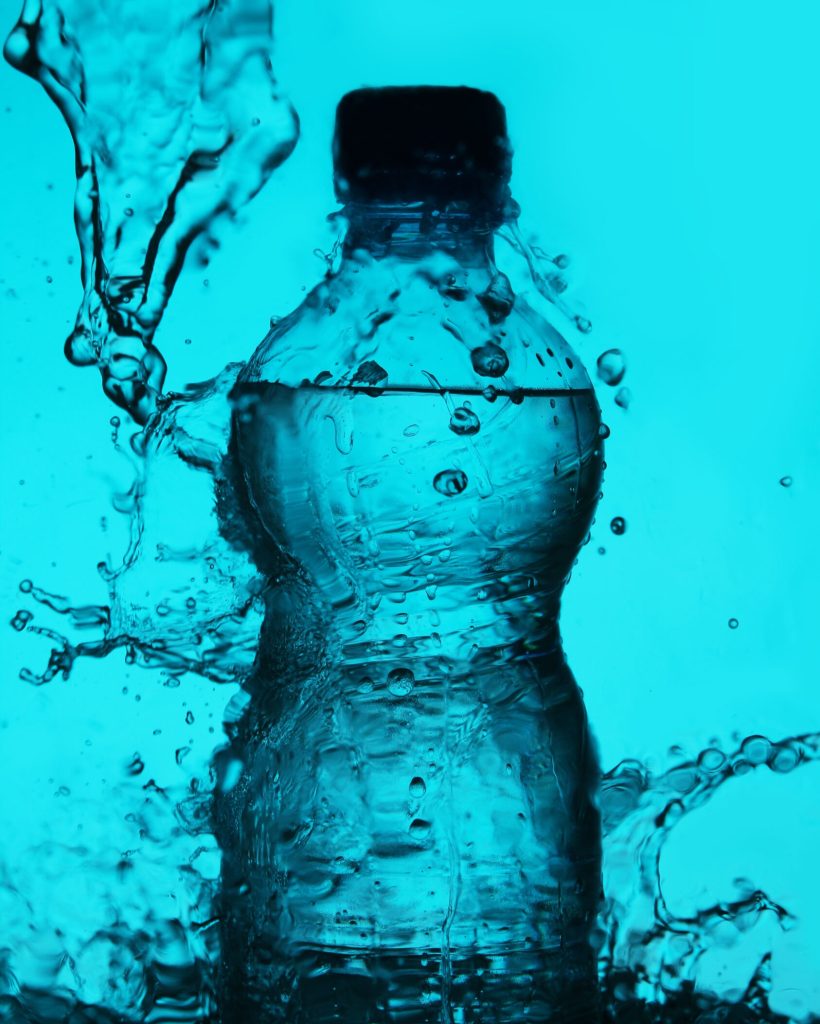 Silhouette of bottle with water splashes over blue background